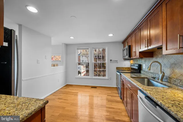 a kitchen with stainless steel appliances granite countertop a sink stove and refrigerator