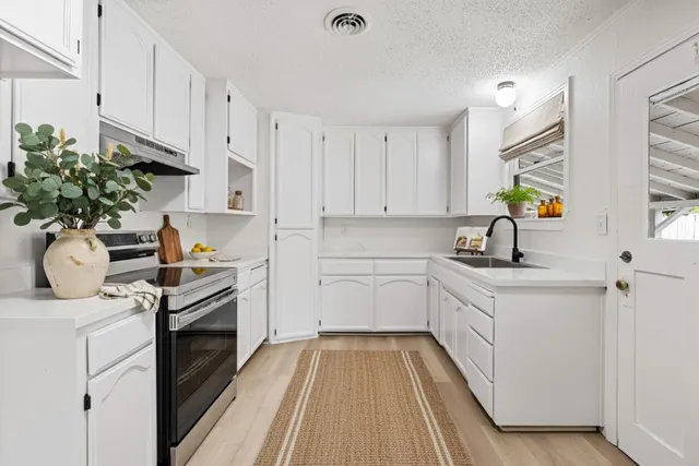 a kitchen with a white stove top oven and white cabinets