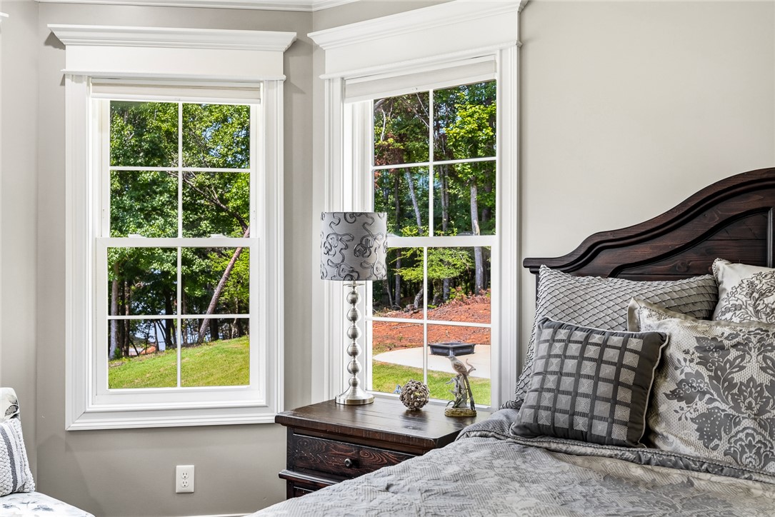 206 James Hare Road Anderson, SC 29626 - Photo 13 of 50 A well-lit bedroom features elegant window frames and tranquil views of the surrounding natural landscape.
