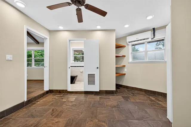 a view of a livingroom with a ceiling fan & windows