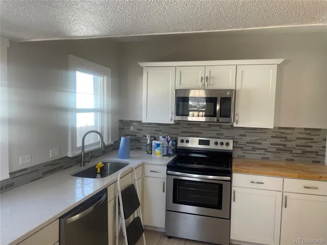 a kitchen with sink a microwave a stove and cabinets