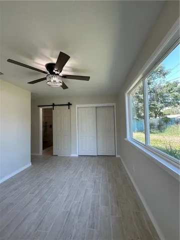 a view of empty room with wooden floor and fan