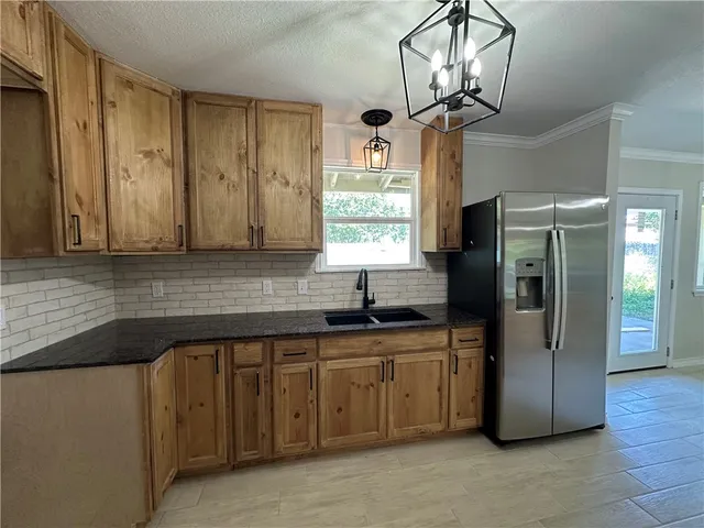 a kitchen with stainless steel appliances granite countertop a sink a refrigerator and a granite counter tops