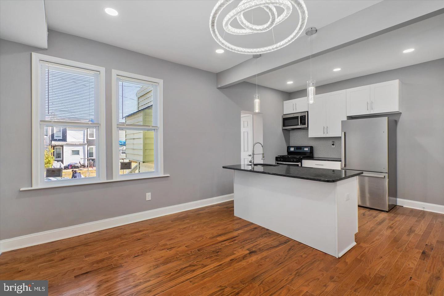 327 Lyndhurst Street Baltimore, MD 21229 - Photo 3 of 44 a kitchen with stainless steel appliances granite countertop a sink a stove a refrigerator cabinets and a large window