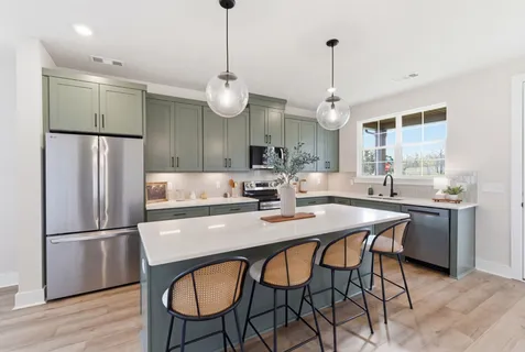 a kitchen with stainless steel appliances granite countertop a dining table chairs refrigerator and wooden cabinets