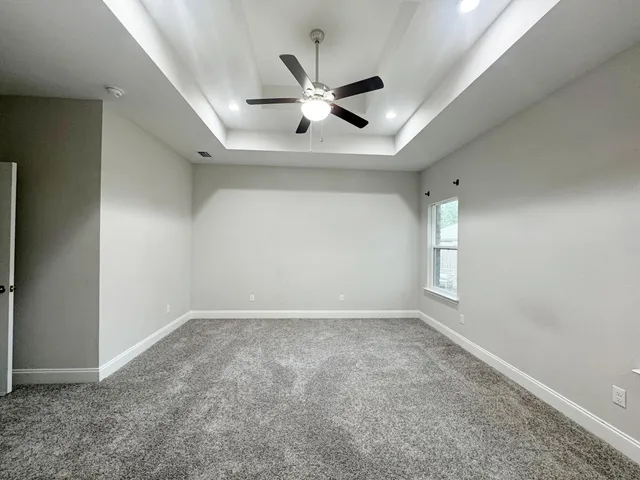 an empty room with ceiling fan and windows