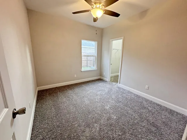 an empty room with windows and fan