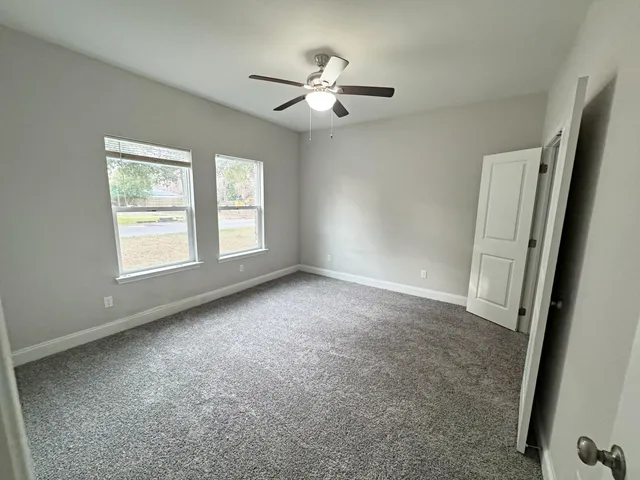 an empty room with windows and fan