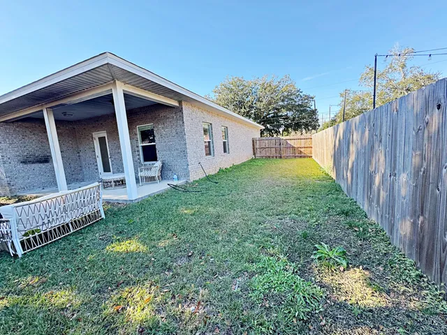 a view of backyard of house with wooden fence