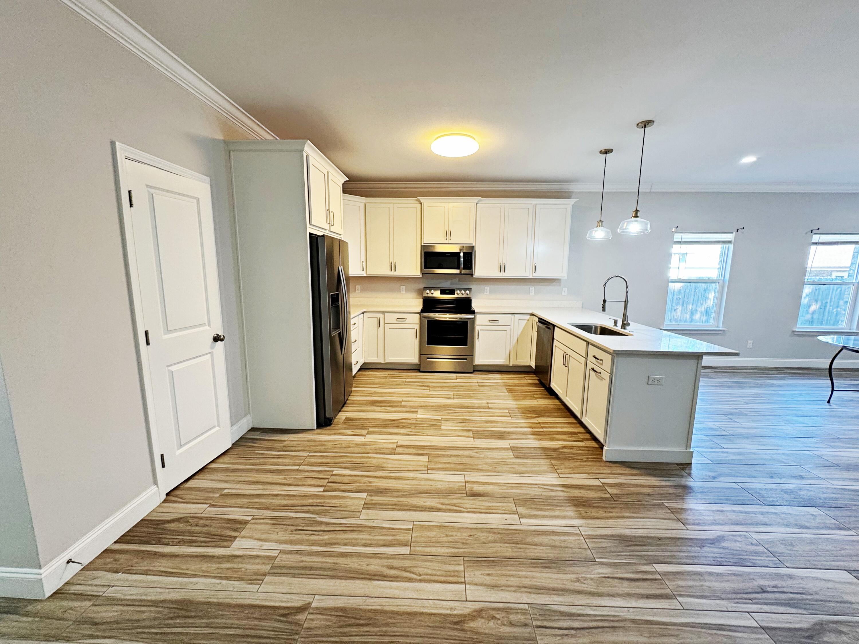 420 Little John Road Mary Esther, FL 32569 - Photo 7 of 37 a large kitchen with kitchen island a stove a sink dishwasher a refrigerator and white cabinets with wooden floor