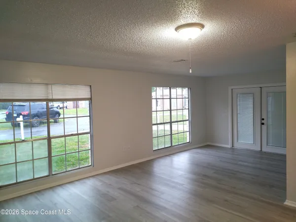 an empty room with wooden floor and windows
