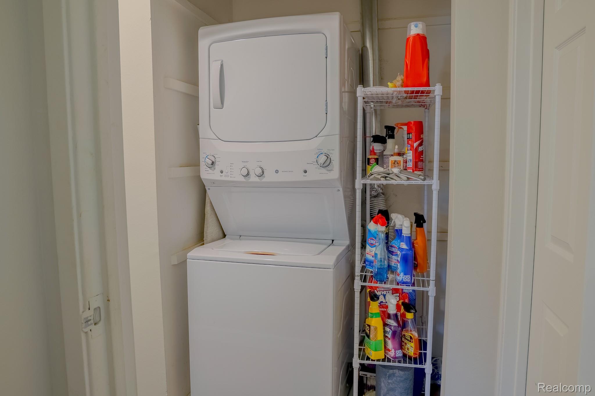 1989 Klingensmith Road, Unit 46 Bloomfield Hills, MI 48302 - Photo 18 of 41 Dedicated laundry area featuring a stacked washer and dryer unit, integrated shelving, and a white interior