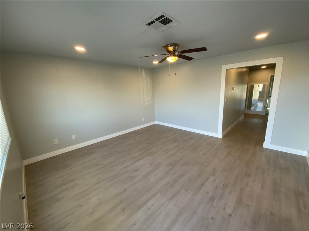 466 East Sunset Road, Unit C Henderson, NV 89011 - Photo 1 of 12 Empty room featuring visible vents, wood finished floors, recessed lighting, baseboards, and ceiling fan