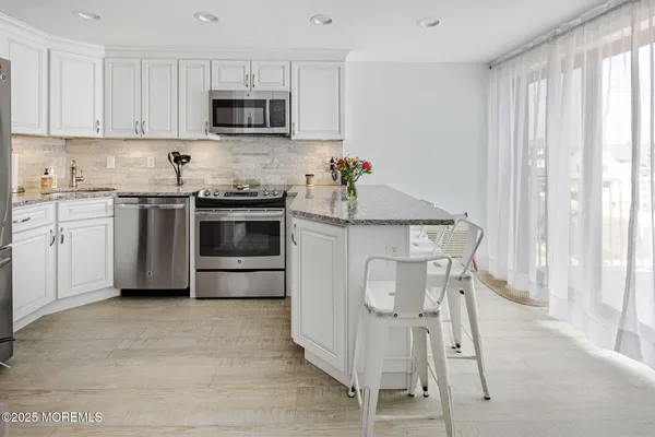 a kitchen with stainless steel appliances granite countertop a stove a sink and white cabinets