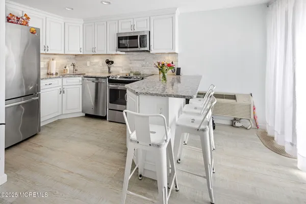 a kitchen with stainless steel appliances a white table chairs and a refrigerator