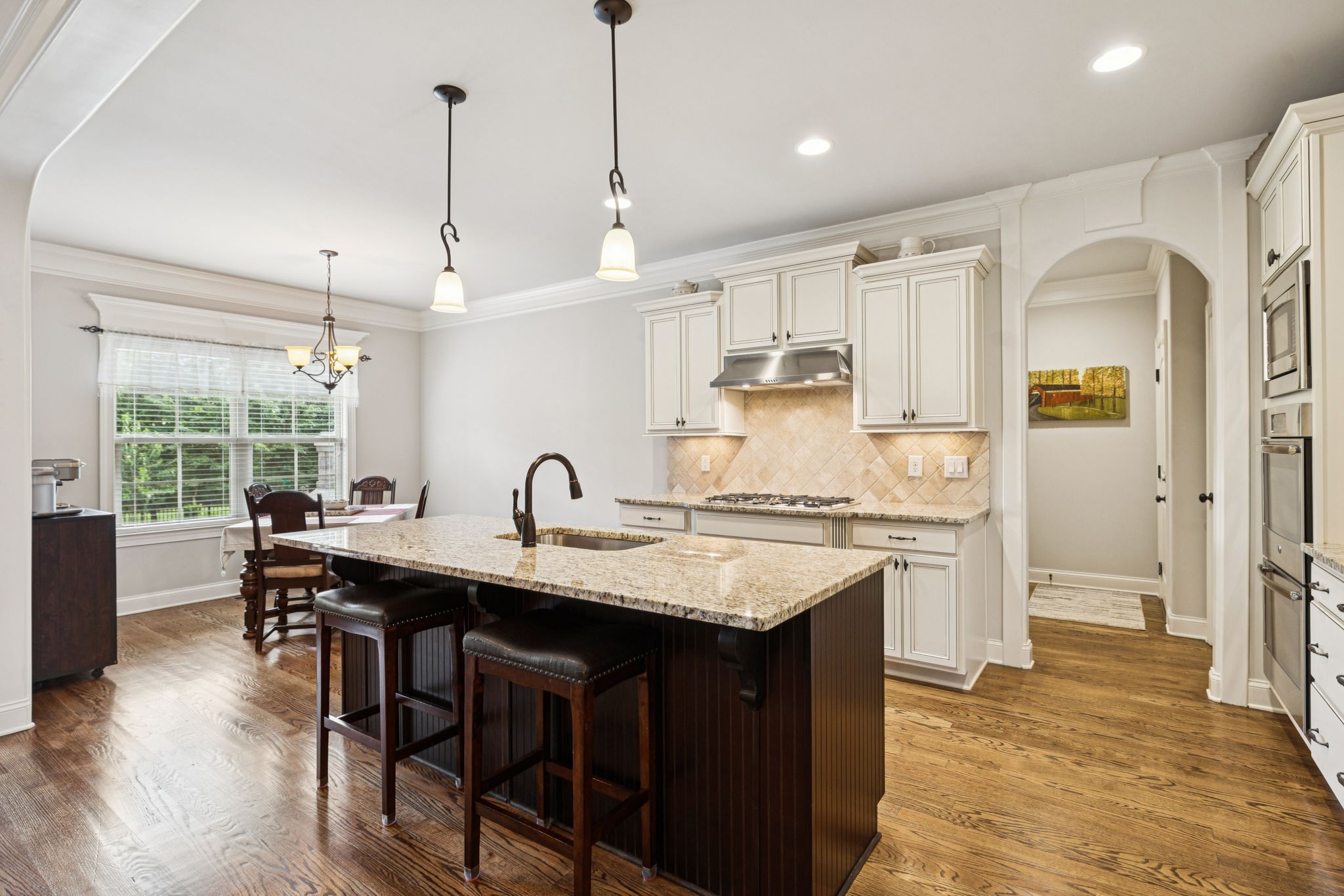 8009 June Apple Lane Spring Hill, TN 37174 - Photo 21 of 69 a kitchen with stainless steel appliances granite countertop a stove a refrigerator a kitchen island a sink dishwasher and white cabinets with wooden floor