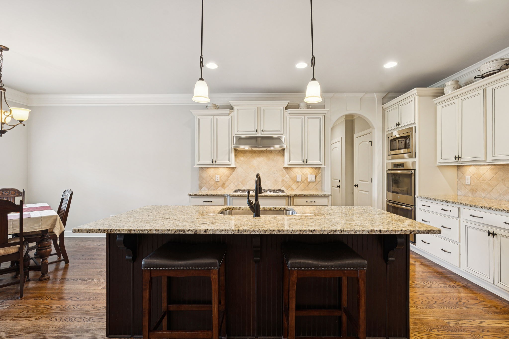 8009 June Apple Lane Spring Hill, TN 37174 - Photo 23 of 69 a kitchen with kitchen island granite countertop a table chairs sink and cabinets