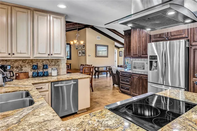 a kitchen with stainless steel appliances granite countertop a sink window and cabinets