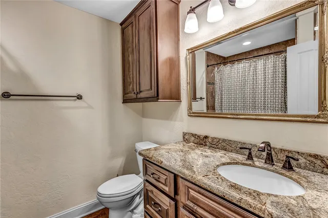 a bathroom with a granite countertop sink toilet and shower