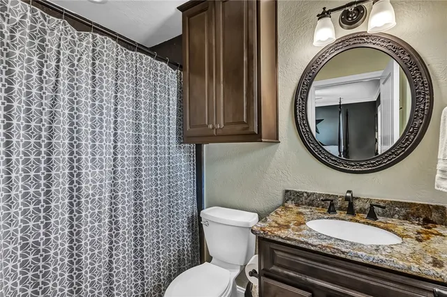 a bathroom with a granite countertop toilet a sink and a mirror