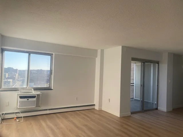 a view of an empty room with wooden floor and closet