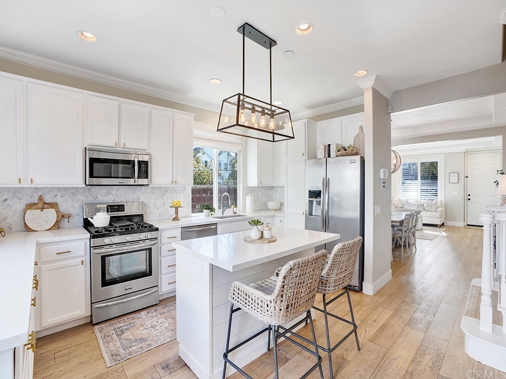 15 Whidbey Drive Ladera Ranch, CA 92694 - Photo 1 of 1 a kitchen with stainless steel appliances a dining table chairs stove refrigerator and microwave
