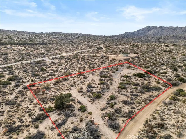 an aerial view of house with yard and mountain view in back