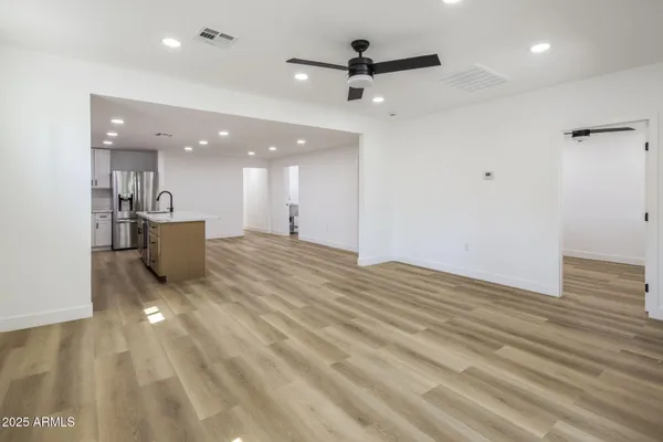a view of a living room a ceiling fan and kitchen view