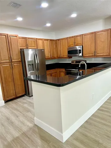 a kitchen with stainless steel appliances granite countertop a refrigerator a sink and a stove