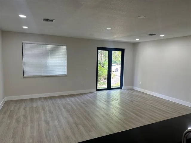 an empty room with wooden floor and windows