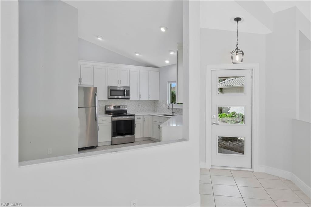 11054 Linnet Lane Naples, FL 34119 - Photo 14 of 50 a kitchen with kitchen island white cabinets and stainless steel appliances