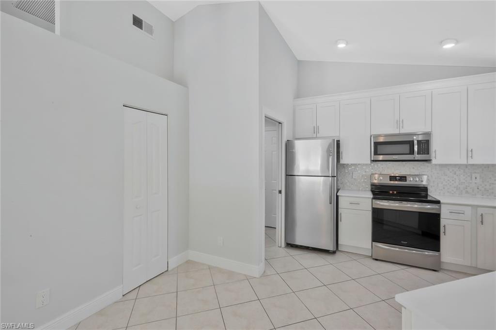 11054 Linnet Lane Naples, FL 34119 - Photo 15 of 50 a kitchen with white cabinets and stainless steel appliances