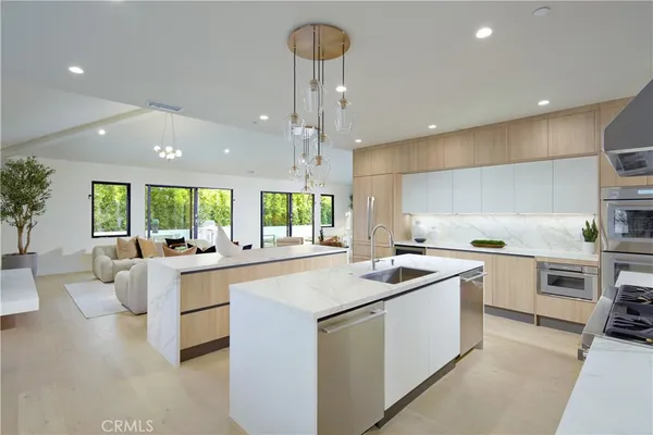 a kitchen that has a lot of white cabinets and stainless steel appliances