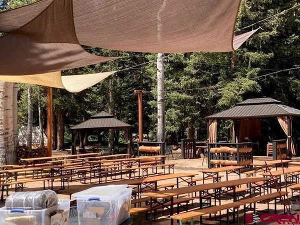a view of a patio with table and chairs under an umbrella with a barbeque