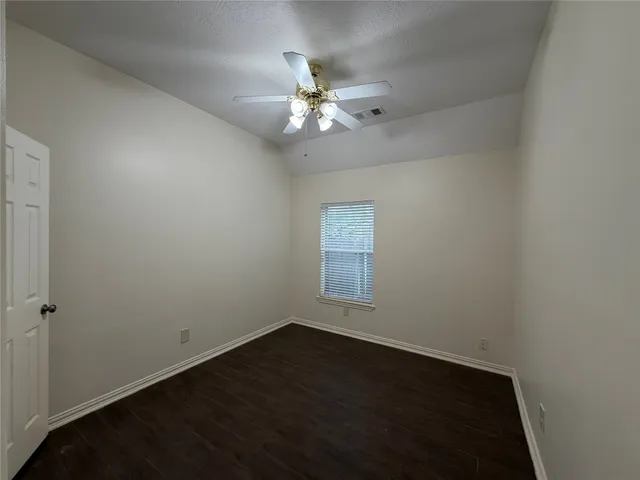 an empty room with a hardwood and ceiling fan