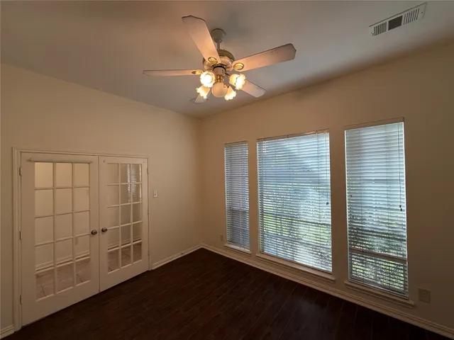 a view of an empty room with a window and wooden floor