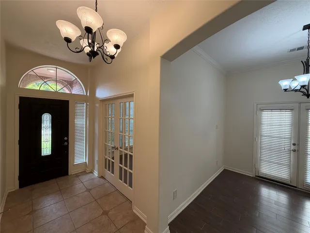 a view of a hallway with wooden floor and a chandelier