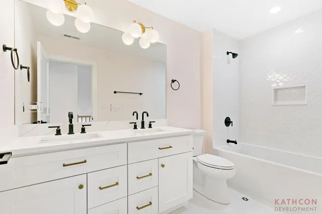 a bathroom with a toilet a sink a mirror a bathtub and vanity