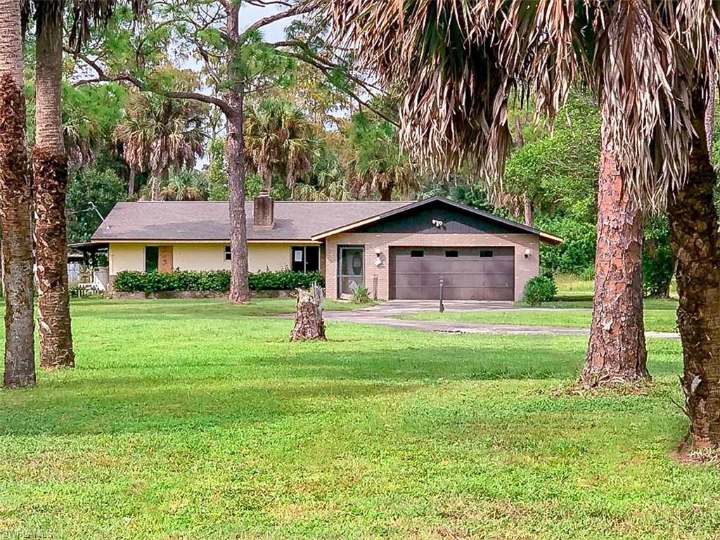 5975 Green Boulevard Naples, FL 34116 - Photo 2 of 20 a front view of a house with a garden and trees