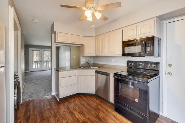 a kitchen with a refrigerator a sink and dishwasher a stove top oven with wooden floor