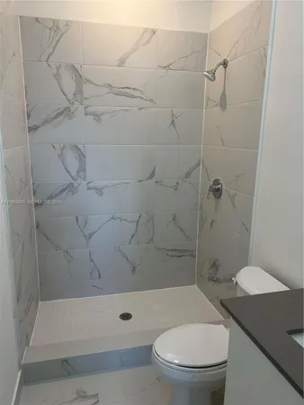 a bathroom with a granite countertop toilet and a sink