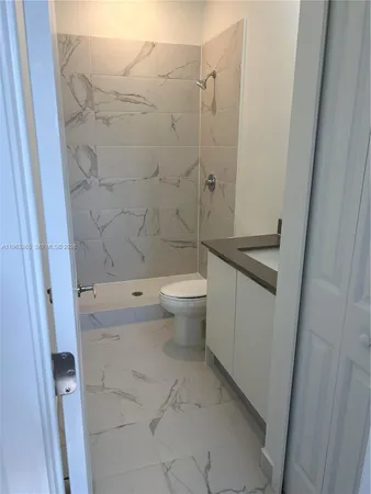 a bathroom with a granite countertop sink a toilet and shower