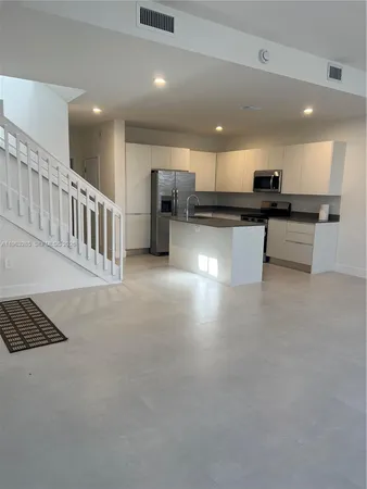 a view of kitchen with kitchen island stainless steel appliances refrigerator stove microwave and stove