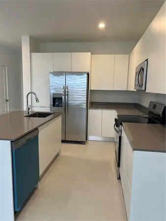 a kitchen with granite countertop a sink and a refrigerator