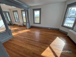 a view of an empty room with wooden floor and a window
