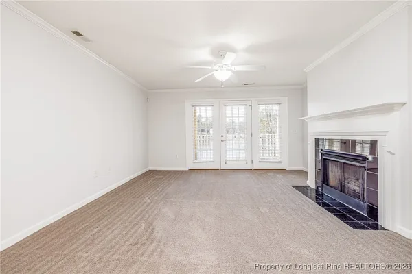 an empty room with windows fireplace and fans