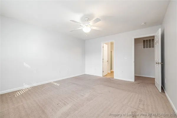 an empty room with closet and a ceiling fan