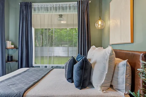a bedroom with a bed and large windows