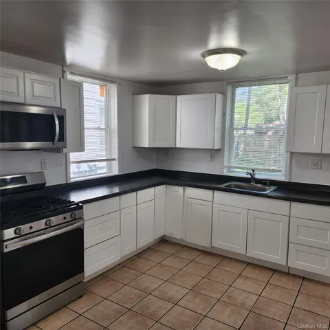 a kitchen with granite countertop a sink a stove top oven and cabinets