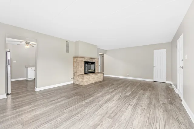 a view of empty room with wooden floor and fireplace